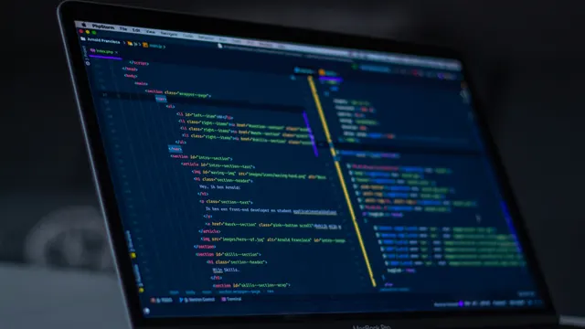 Laptop z otwartym edytorem kodu HTML w ciemnym, przyciemnionym wnętrzu