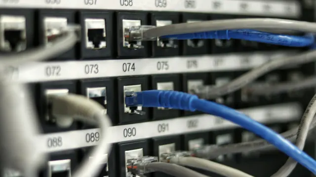 Niebieskie i szare kable sieciowe wpięte w ponumerowane gniazda panelu krosowego