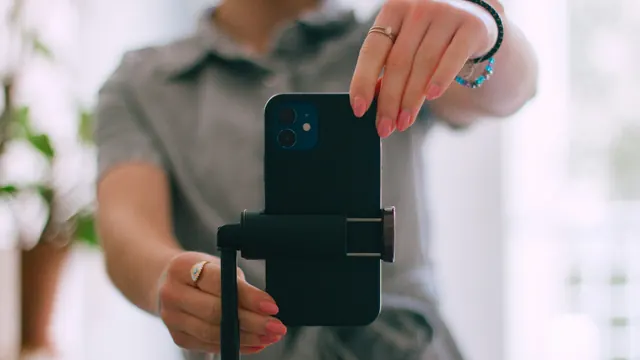 Kobieta ustawia smartfon pionowo w uchwycie statywu w jasnym wnętrzu z roślinami